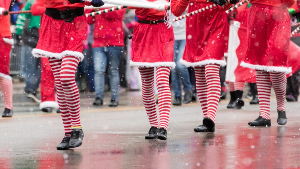 Bodies of people in holiday wear marching in parade